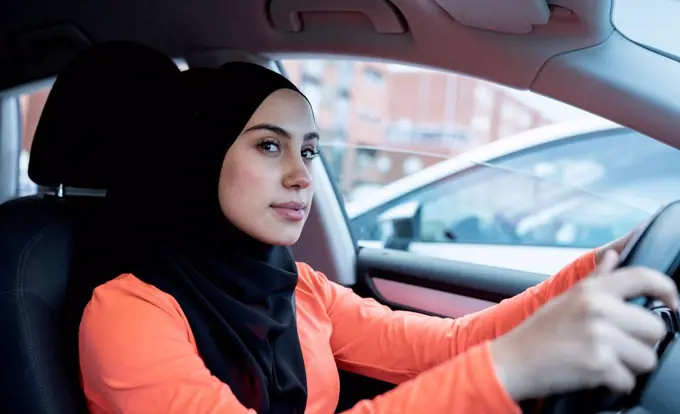 Thoughtful Arab woman looking away while driving car