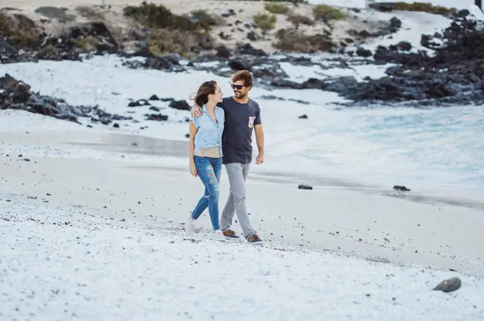 Mid adult couple talking while walking at beach