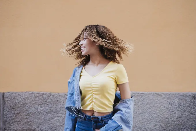 Beautiful woman with tousled hair by wall