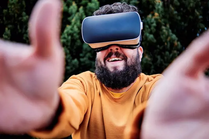 Smiling man wearing virtual reality simulator in garden