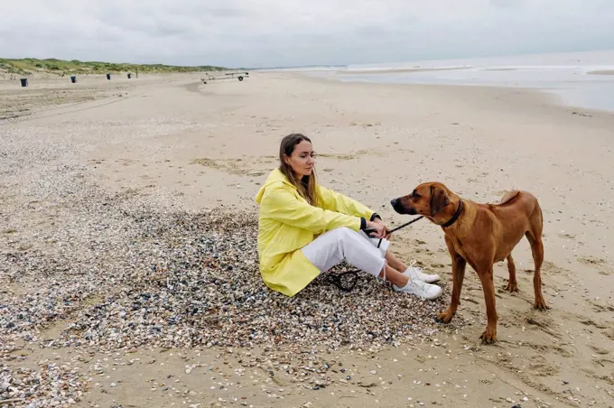 Woman with dog spending leisure time at beach