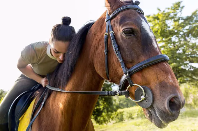 Woman leaning while sitting on horse