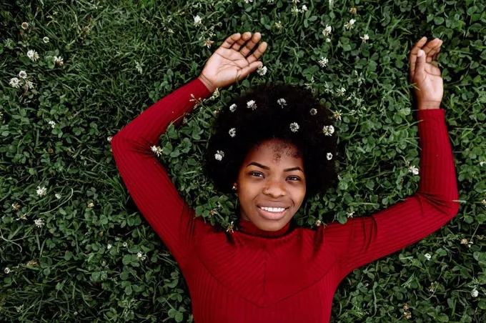 Young woman wearing flowers while lying on grass