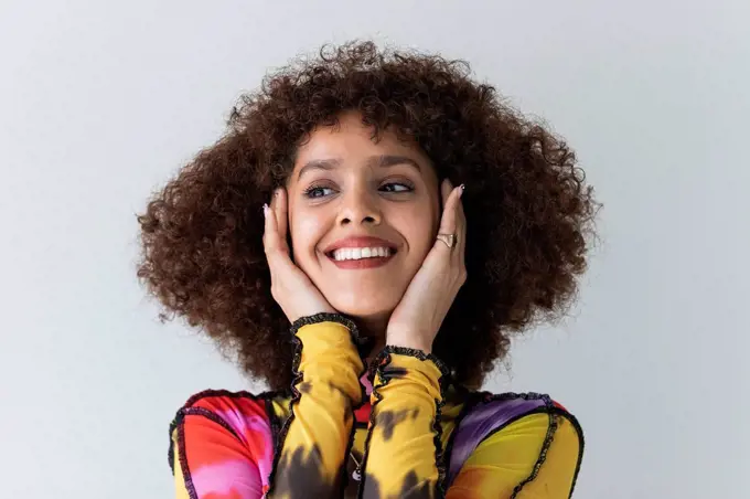 Curly hair woman smiling while looking away against white background