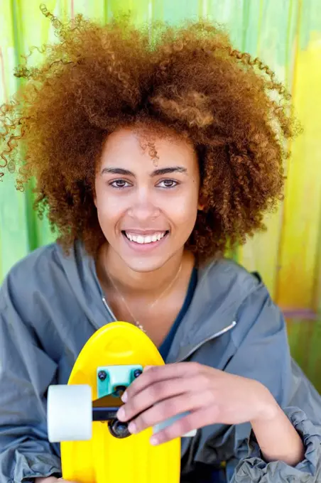 Afro young woman with yellow skateboard