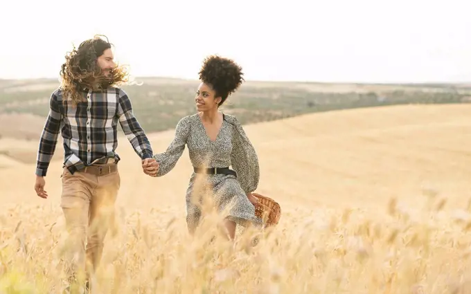 Couple looking at each other while walking on wheat field