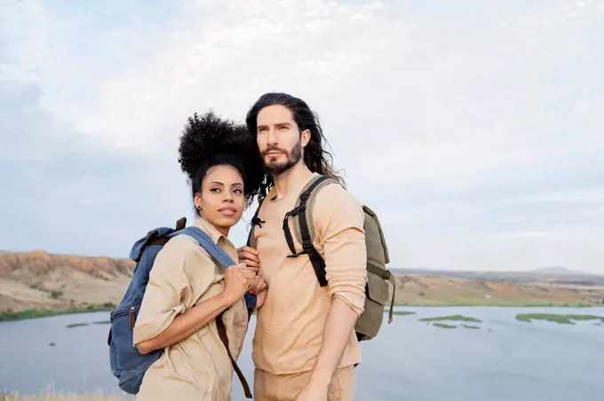 Girlfriend with backpack looking away while standing by boyfriend