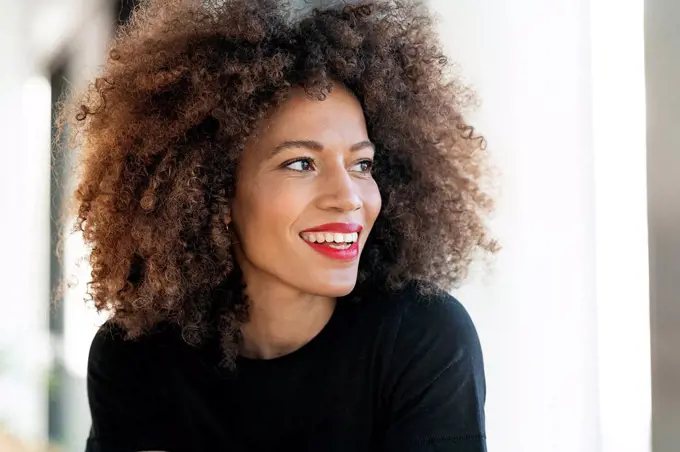 Smiling businesswoman with frizzy hair looking away in office