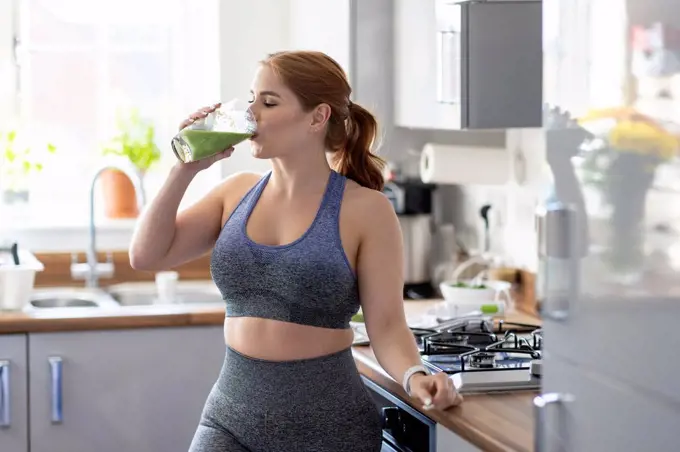 Redhead woman drinking healthy milkshake after working out at home