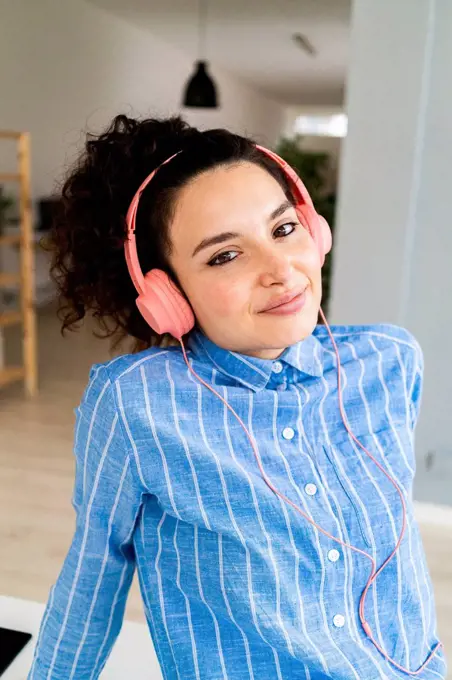 Smiling businesswoman with headphones listening music in office