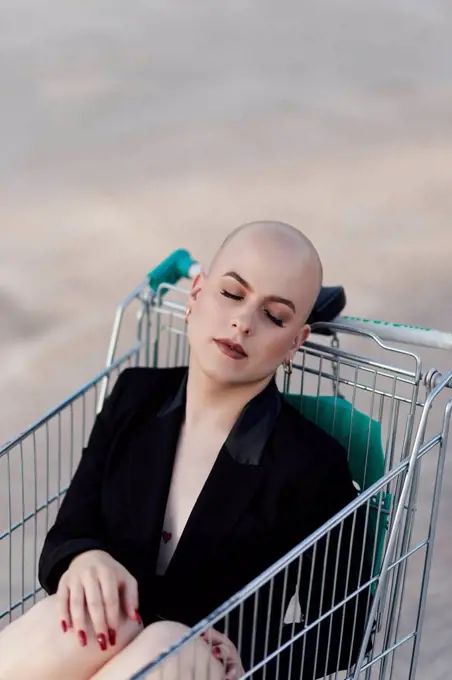 Bald transgender woman sleeping in shopping cart