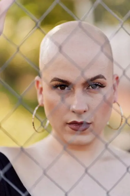 Serious transgender woman seen through chainlink fence