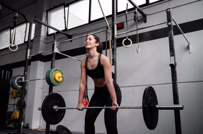 Active woman lifting weight in gym