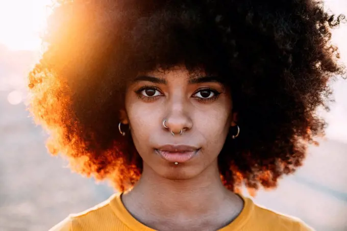 Afro woman with pierced nose during sunset