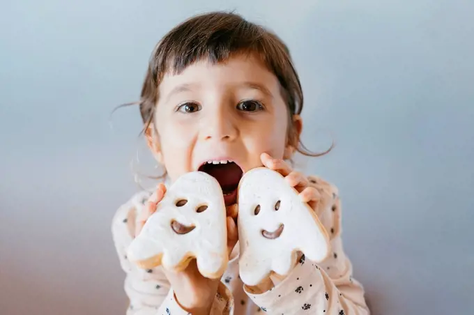 Mischievous little girl with mouth open showing ghost cookies