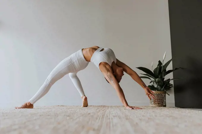 Flexible yogi practicing while bending over backwards at yoga studio