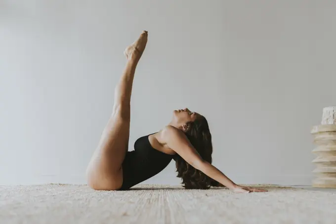 Flexible yogi with feet up practicing yoga at health club