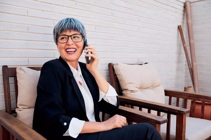 Businesswoman looking away while talking on smart phone at backyard