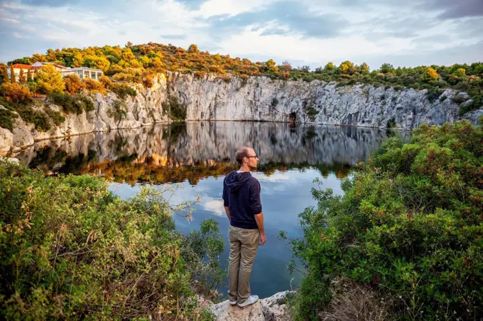 Man standing on rock formation while looking at Lake Dragon's Eye, Rogoznica, Croatia