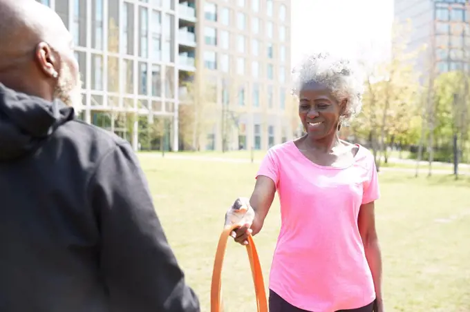Smiling woman giving resistance band to man at park