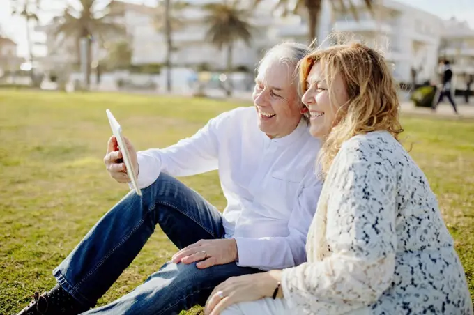 Happy mature couple doing video call through digital tablet during sunny day