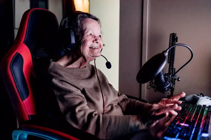 Senior woman wearing headset while using computer at home