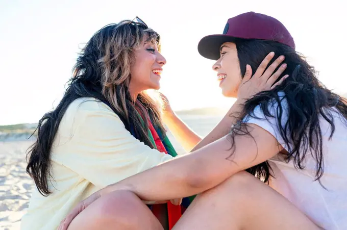 Lesbian couple looking at each other while sitting at beach