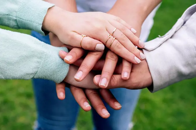 Male and female friends stacking hands