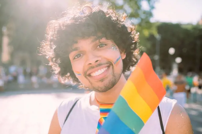 Male activist with rainbow flag in pride event on sunny day