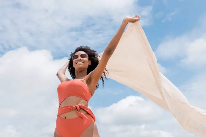 Young woman holding beach towel on sunny day