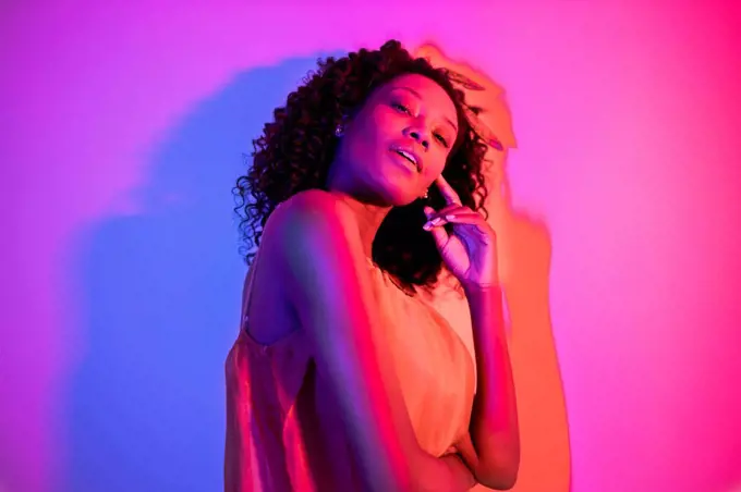 Young woman with head cocked against colored background