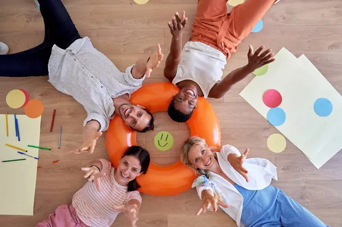 Happy male and female colleagues lying on inflatable ring in office