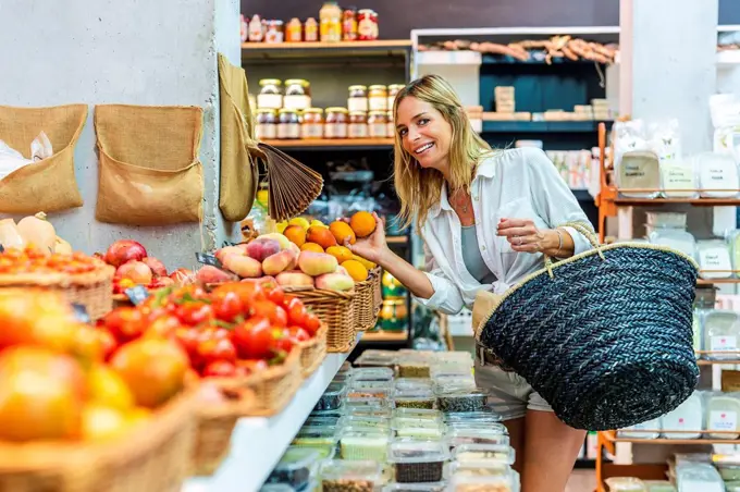 Woman carrying basket while buying fruits at supermarket