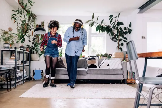 Happy father and daughter dancing together in living room