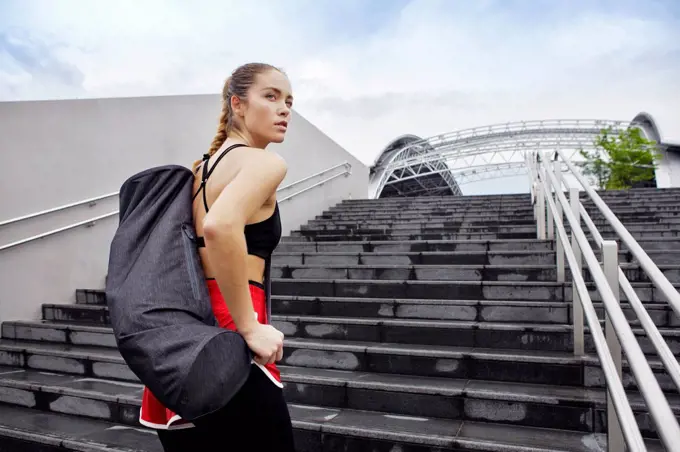 Female athlete with bag standing on steps