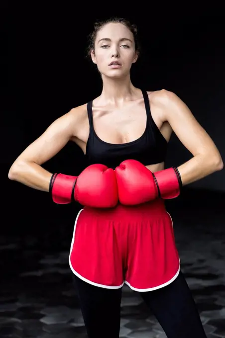 Confident female athlete wearing boxing gloves standing at basement