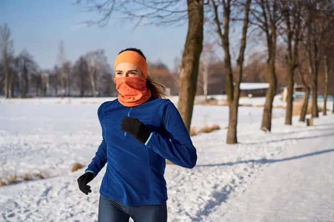 Woman wearing gaiter face mask while running during winter