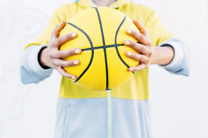 Young woman holding yellow basketball