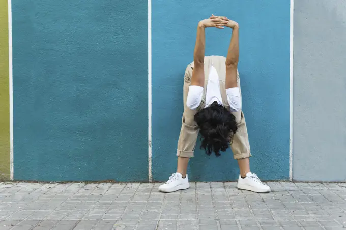 Flexible young woman doing stretching exercise on footpath