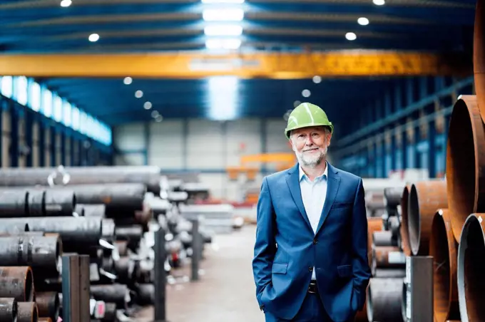 Smiling male managing director standing with hands in pockets at warehouse