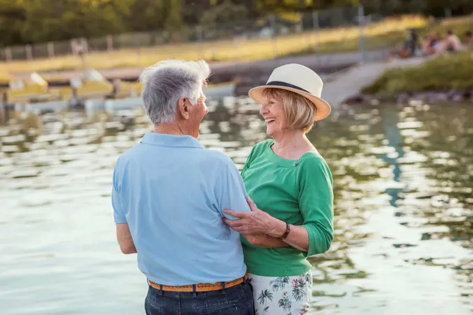 Cheerful senior couple looking at each other while standing by lake