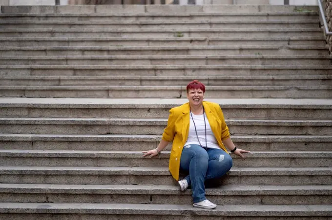 Happy mature woman sitting on steps