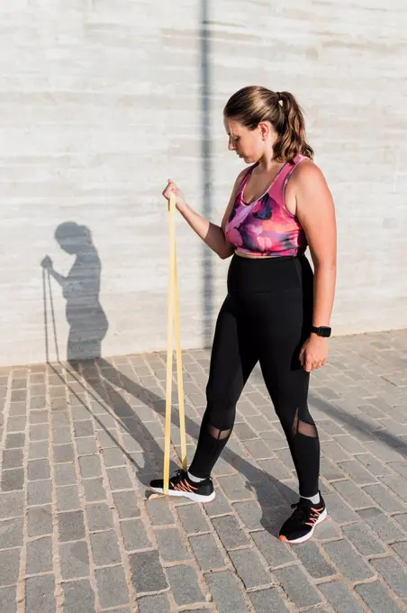 Young female athlete with resistance band practicing during sunny day