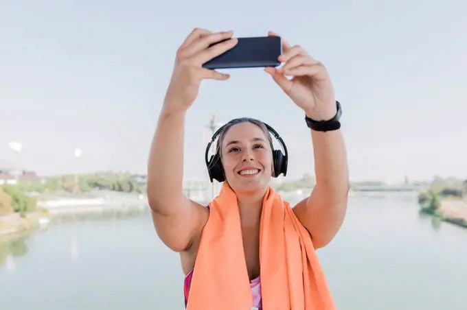 Young female athlete taking selfie through smart phone