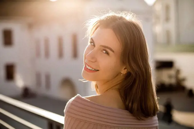 Smiling young woman on rooftop during sunny day