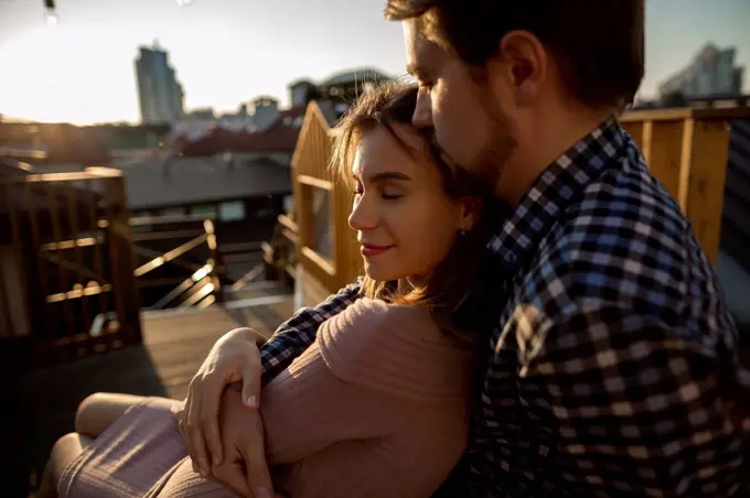 Girlfriend with eyes closed leaning on boyfriend at rooftop