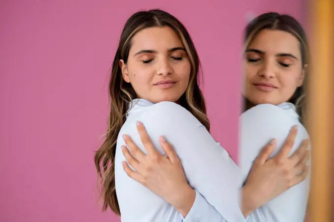 Businesswoman hugging herself by pink wall