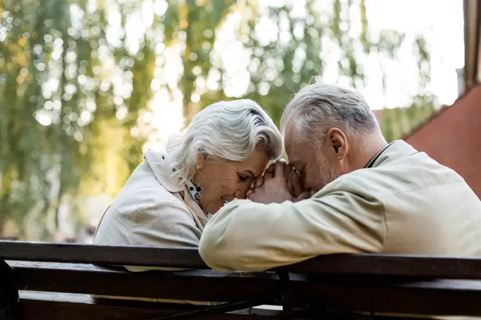 Couple holding hand while sitting with face to face on bench