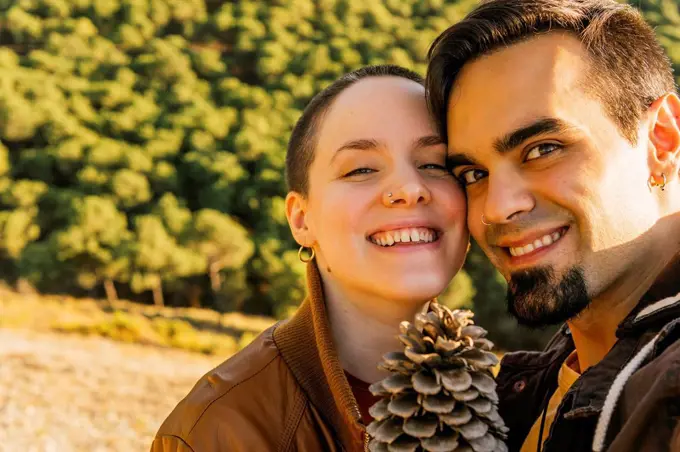 Smiling couple with pine cone on mountain