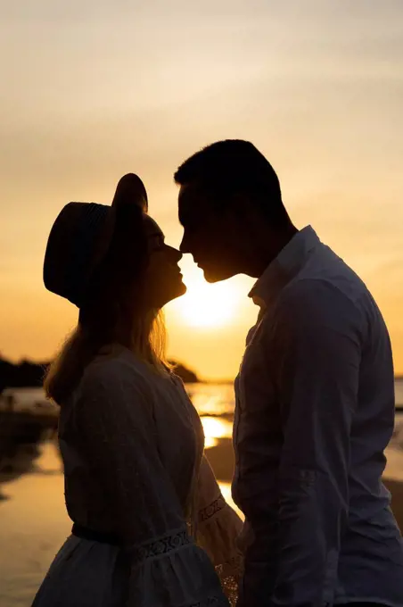 Girlfriend rubbing nose with boyfriend at beach on sunset